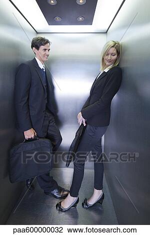 Stock Image - Colleagues playing footsies in elevator. Fotosearch