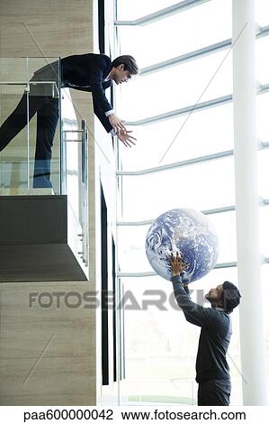 Stock Image - Colleagues throwing ball in lobby. Fotosearch