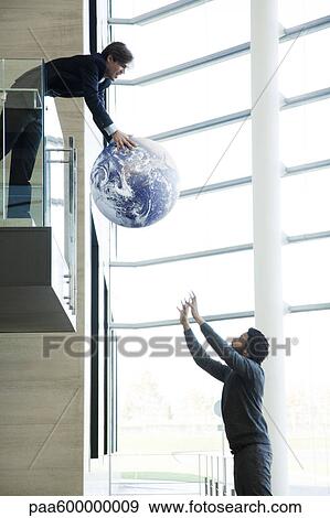 Stock Photo - Colleagues throwing ball in lobby. Fotosearch