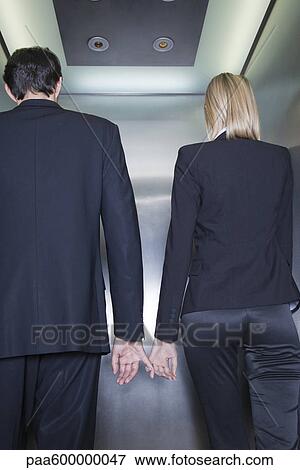 Professionals holding hands in elevator, rear view View Large Photo Image Stock Photo - Professionals holding hands in elevator, rear view. Fotosearch
