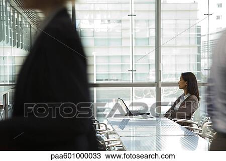 Stock Image - Businesswoman looking away in thought, people walking in foreground. Fotosearch