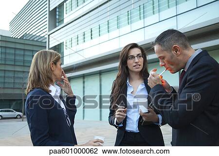 Colleagues taking smoke break outdoors View Large Photo Image Stock Image - Colleagues taking smoke break outdoors. Fotosearch