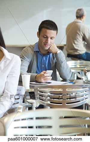 Man using cell phone in cafeteria View Large Photo Image Stock Photo - Man using cell phone in cafeteria. Fotosearch
