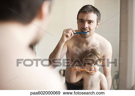 Stock Photo - Father and toddler son brushing their teeth together. Fotosearch