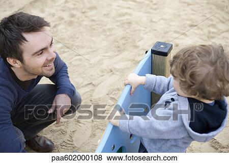 Stock Photo - Father and toddler son playing on playground. Fotosearch