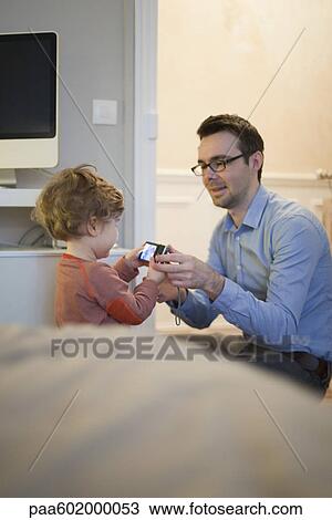 Stock Image - Father and young son looking at digital camera together. Fotosearch