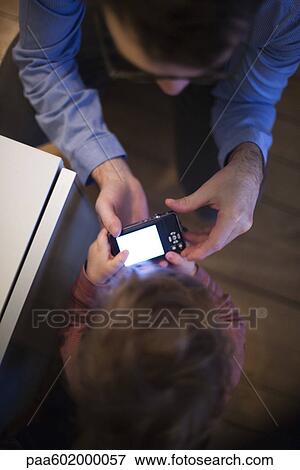 Stock Photo - Father and young son looking at digital camera together, overhead view. Fotosearch