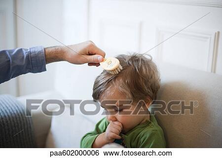 Stock Photograph - Father brushing toddler son's hair, cropped. Fotosearch