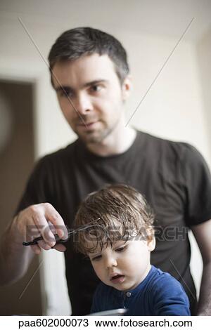 Stock Image - Father cutting toddler son's hair. Fotosearch