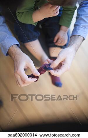 Picture - Father helping toddler put on socks, cropped. Fotosearch