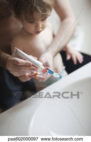 Stock Photo - Father helping toddler son brush his teeth. Fotosearch