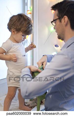 Stock Photo - Father helping toddler son get dressed. Fotosearch