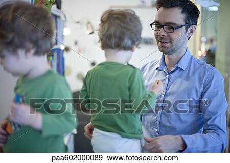 Stock Photo - Father helping toddler son get dressed. Fotosearch