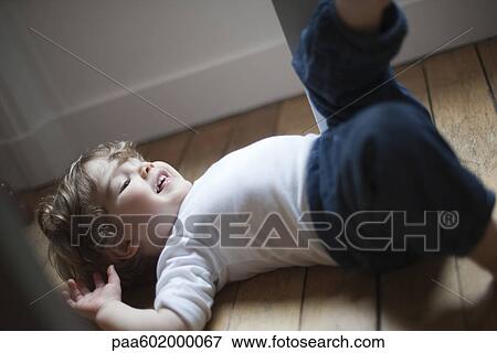 Little boy lying on floor laughing View Large Photo Image Stock Photo - Little boy lying on floor laughing. Fotosearch