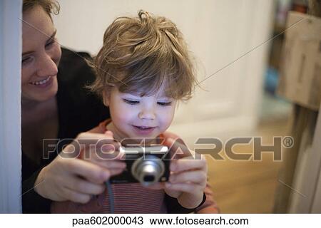 Mother and toddler son looking at digital camera together View Large Photo Image Stock Image - Mother and toddler son looking at digital camera together. Fotosearch