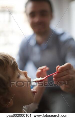 Stock Image - Toddler being fed spoonful of food. Fotosearch