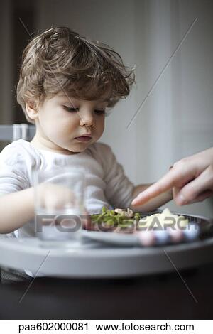 Stock Image - Toddler boy being told to eat his vegetables, cropped. Fotosearch