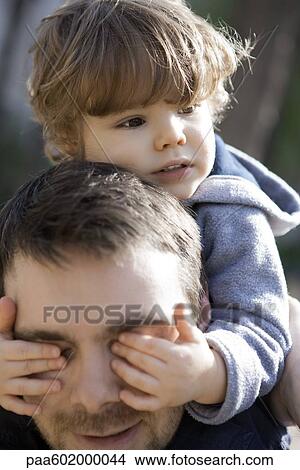 Picture - Toddler boy covering father's eyes with his hands, portrait. Fotosearch