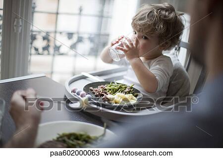 Stock Image - Toddler boy drinking glass of water. Fotosearch
