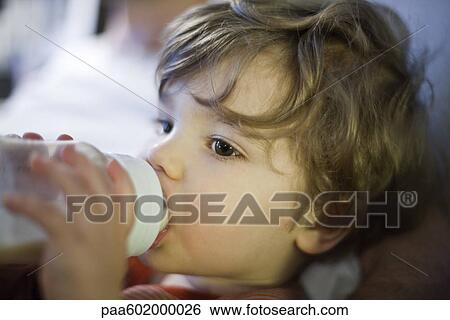 Toddler boy drinking milk from baby bottle View Large Photo Image Stock Photograph - Toddler boy drinking milk from baby bottle. Fotosearch