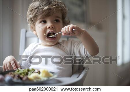 Toddler boy feeding himself View Large Photo Image Stock Image - Toddler boy feeding himself. Fotosearch