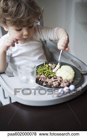 Stock Photo - Toddler boy feeding himself. Fotosearch