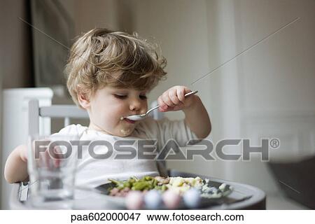 Toddler boy feeding himself with spoon View Large Photo Image Stock Photo - Toddler boy feeding himself with spoon. Fotosearch