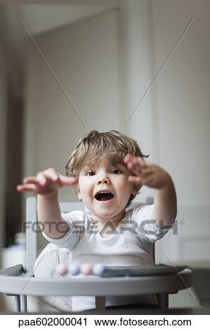 Stock Image - Toddler boy playing in high chair. Fotosearch