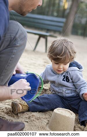 Toddler boy playing in sand with his father View Large Photo Image Stock Photo - Toddler boy playing in sand with his father. Fotosearch