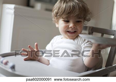 Toddler boy sitting in high chair at snacktime View Large Photo Image Stock Image - Toddler boy sitting in high chair at snacktime. Fotosearch