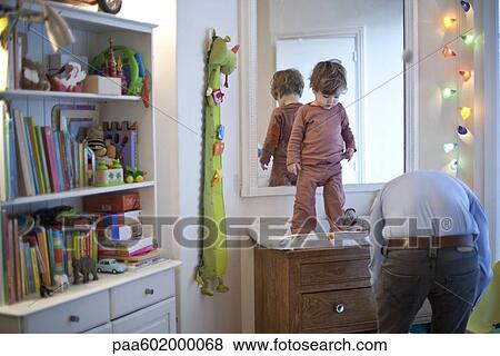 Toddler boy standing on top of changing table in nursery View Large Photo Image Stock Photo - Toddler boy standing on top of changing table in nursery. Fotosearch