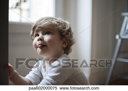 Stock Photography - Toddler boy sticking out tongue, looking up, portrait. Fotosearch