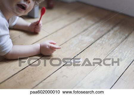 Toddler lying on floor with spoon in hand, pointing to spilled food View Large Photo Image Stock Image - Toddler lying on floor with spoon in hand, pointing to spilled food. Fotosearch