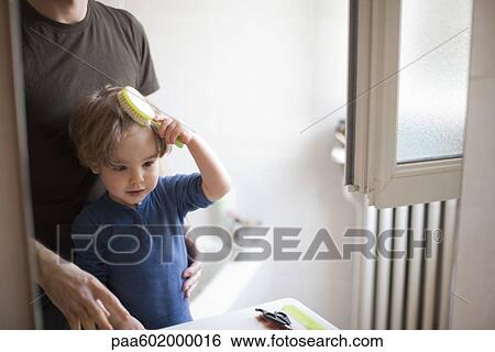Stock Photograph - Young boy learning to brush his hair. Fotosearch