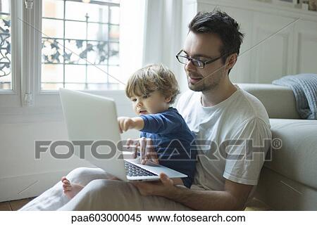 Father and young son looking at laptop computer together View Large Photo Image Stock Photography - Father and young son looking at laptop computer together. Fotosearch