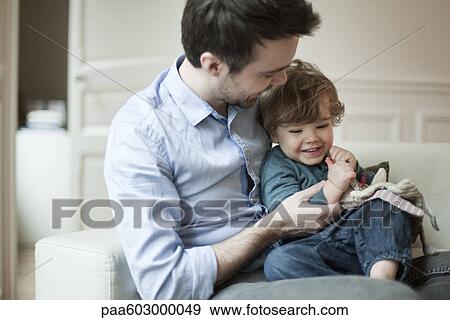 Father and young son playing on couch View Large Photo Image Stock Photo - Father and young son playing on couch. Fotosearch