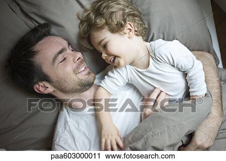 Father and young son relaxing together in bed, portrait View Large Photo Image Stock Image - Father and young son relaxing together in bed, portrait. Fotosearch