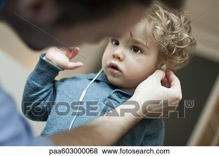 Father helping toddler son use earphones View Large Photo Image Stock Photo - Father helping toddler son use earphones. Fotosearch