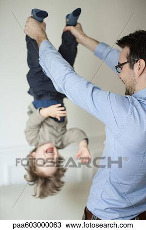 Father holding young son upside down by his ankles View Large Photo Image Stock Image - Father holding young son upside down by his ankles. Fotosearch