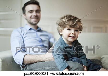 Toddler boy and father sitting on couch View Large Photo Image Stock Image - Toddler boy and father sitting on couch. Fotosearch