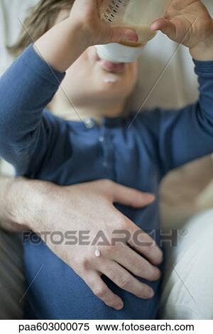 Toddler boy drinking milk from bottle in father's arms View Large Photo Image Stock Photography - Toddler boy drinking milk from bottle in father's arms. Fotosearch