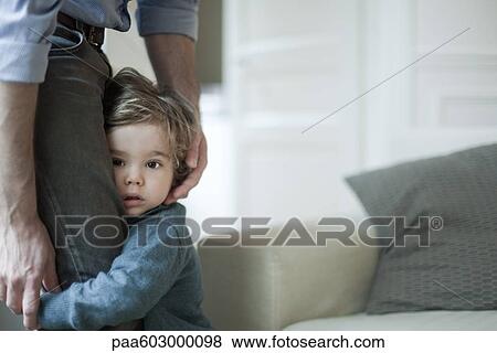 Toddler boy holding on to father's legs View Large Photo Image Stock Photo - Toddler boy holding on to father's legs. Fotosearch