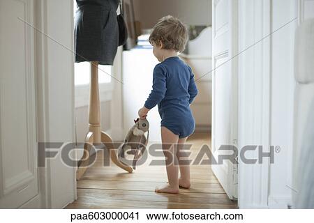 Toddler boy holding toy at home, rear view View Large Photo Image Stock Image - Toddler boy holding toy at home, rear view. Fotosearch
