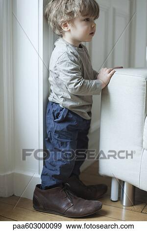 Stock Photo - Toddler boy in father's shoes, portrait. Fotosearch