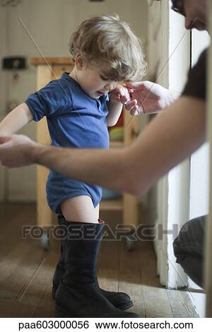 Toddler boy learning to walk in father's boots View Large Photo Image Stock Photograph - Toddler boy learning to walk in father's boots. Fotosearch