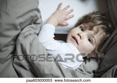 Toddler boy lying in bed, portrait View Large Photo Image Stock Image - Toddler boy lying in bed, portrait. Fotosearch