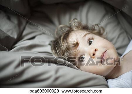 Toddler boy lying in bed, portrait View Large Photo Image Stock Photo - Toddler boy lying in bed, portrait. Fotosearch
