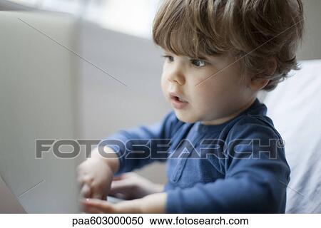 Stock Image - Toddler boy playing with laptop computer, portrait. Fotosearch