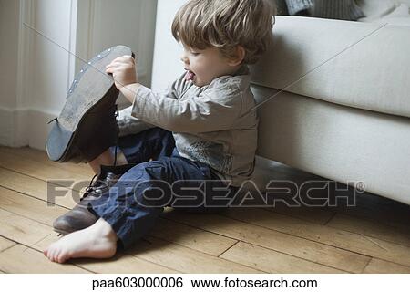 Stock Photograph - Toddler boy playing with parent's shoes. Fotosearch