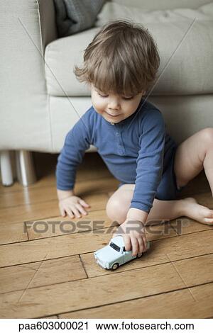 Stock Image - Toddler boy playing with toy car. Fotosearch